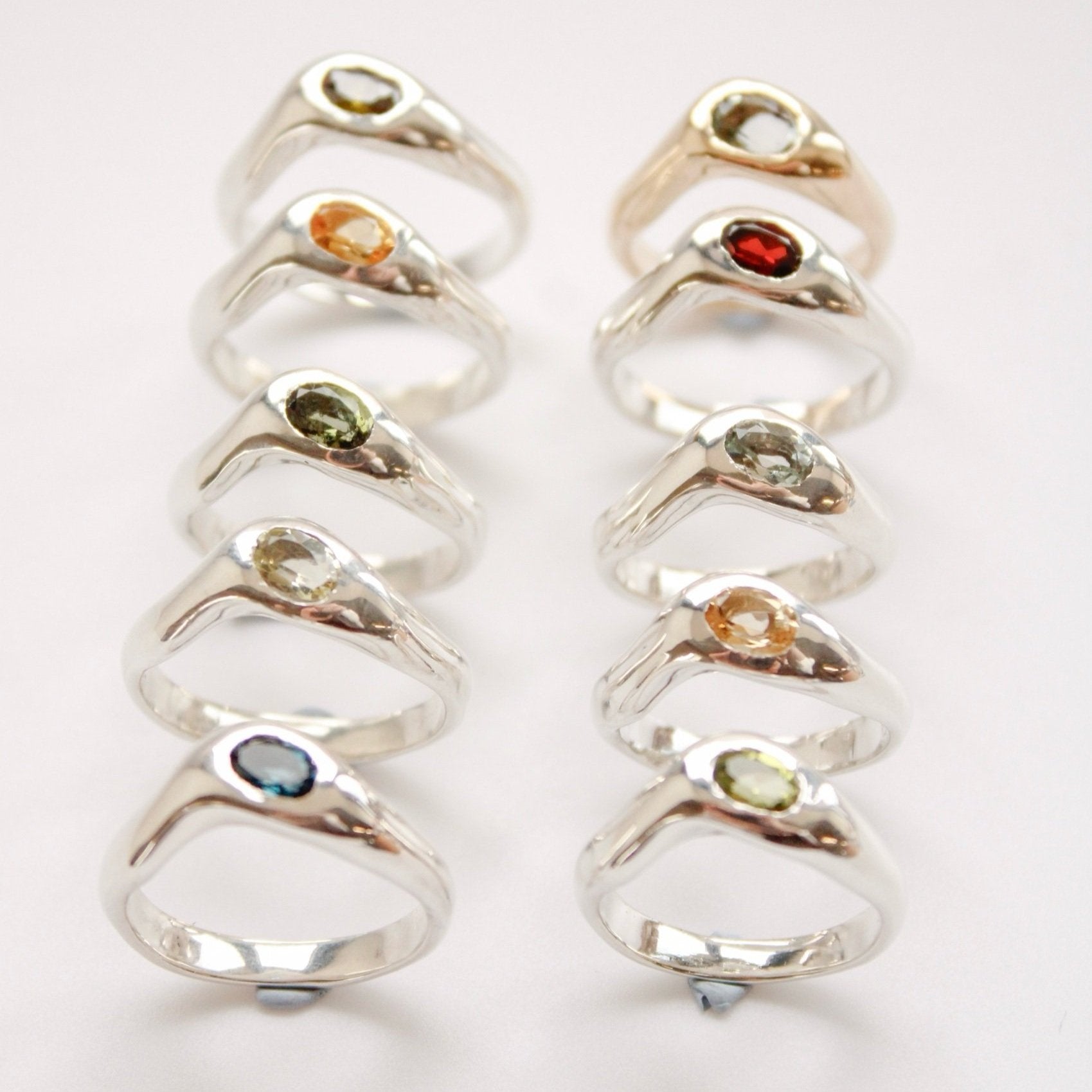 Nine The Silk ring (Copy) handmade sterling silver rings with smooth, rounded bands showcase vibrant green, red, blue, orange, and yellow gemstones. Each is beautifully arranged in three rows on a white background.
