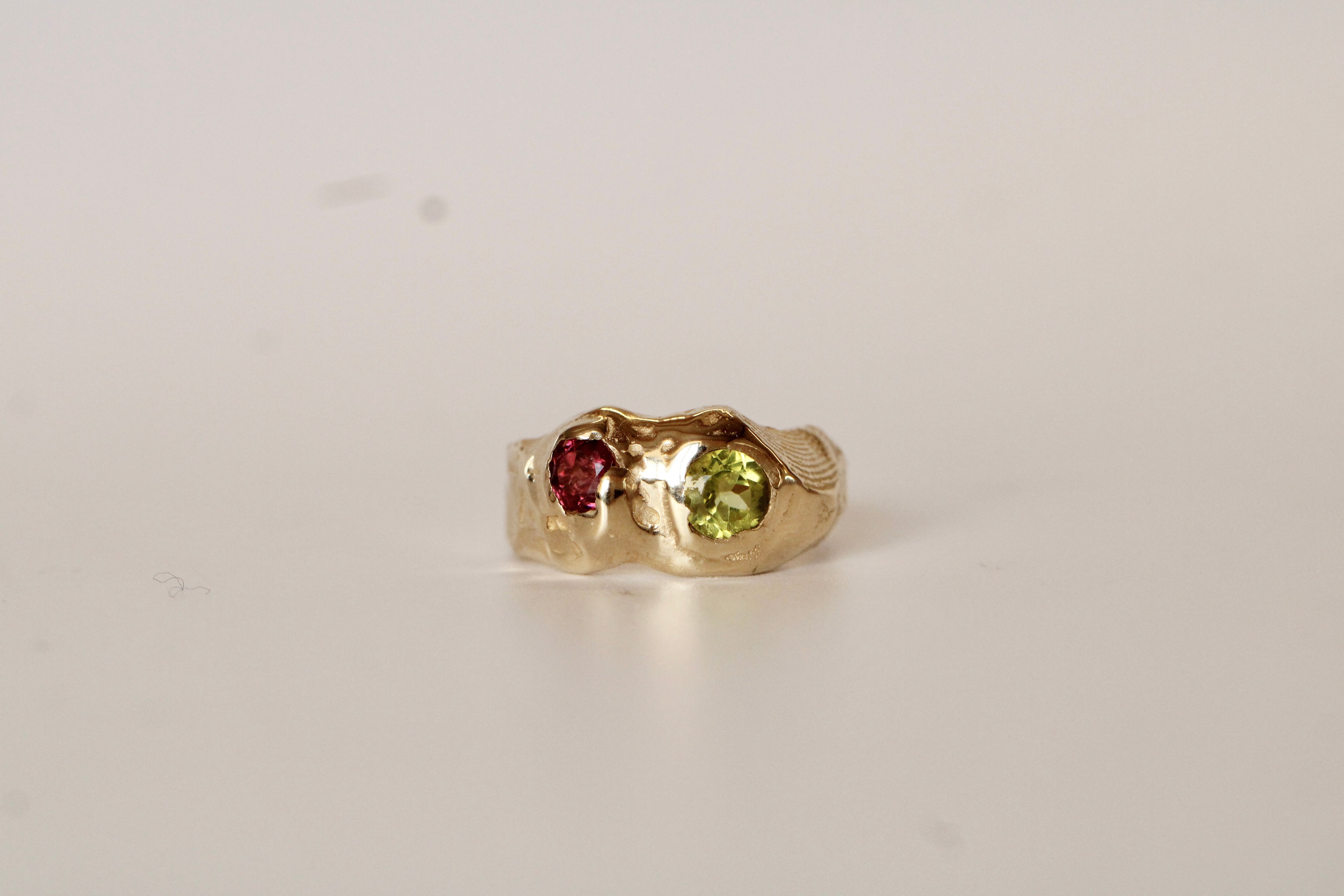 Gold ring with a green gemstone and a red gemstone